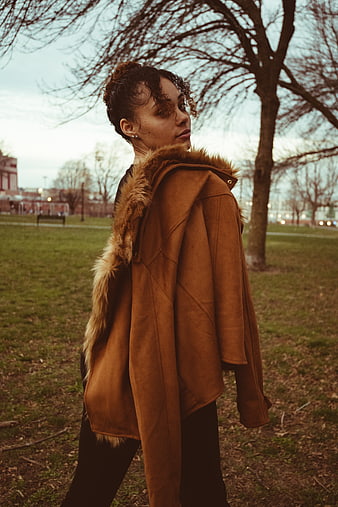 Woman in brown fur hooded jacket looking back in park
