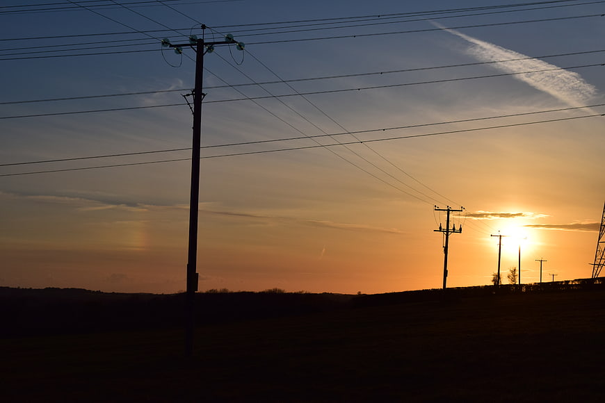 Silhouetted power lines against a vibrant sunset sky