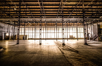 Empty industrial warehouse interior with large windows and steel beams