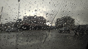 Raindrops on car windshield with blurred city background