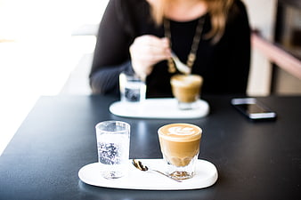 Latte art coffee and water on black table in cafe