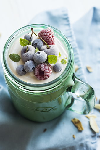 Overhead view of green smoothie with frozen berries in glass jar