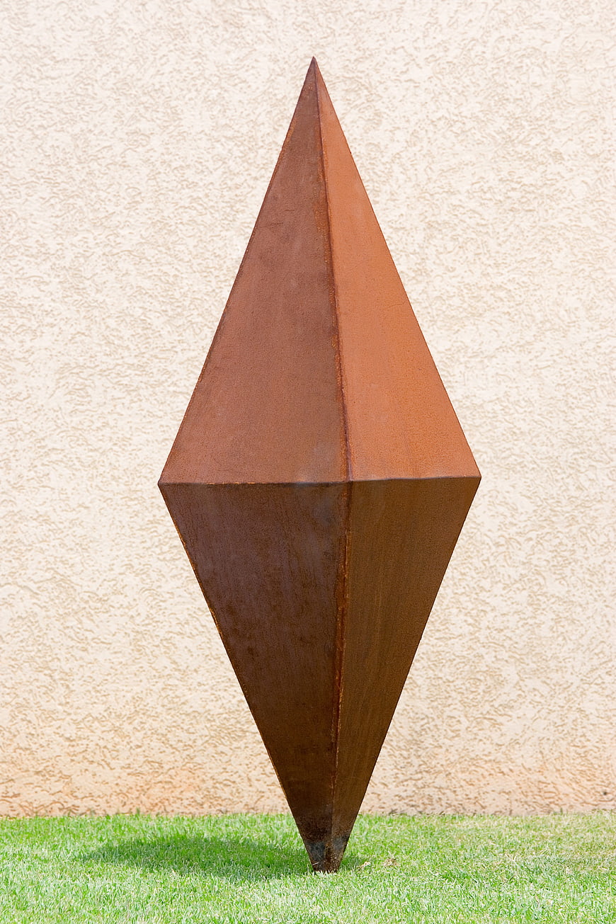 Rusted Metal Geometric Sculpture Standing On Green Grass