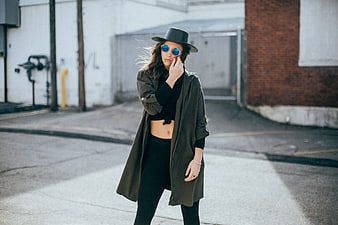 Stylish woman in trench coat and hat posing in urban alley