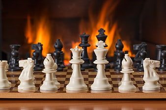 Chess pieces on board with fireplace background