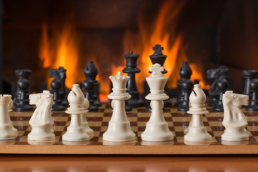 Chess pieces on board with fireplace background