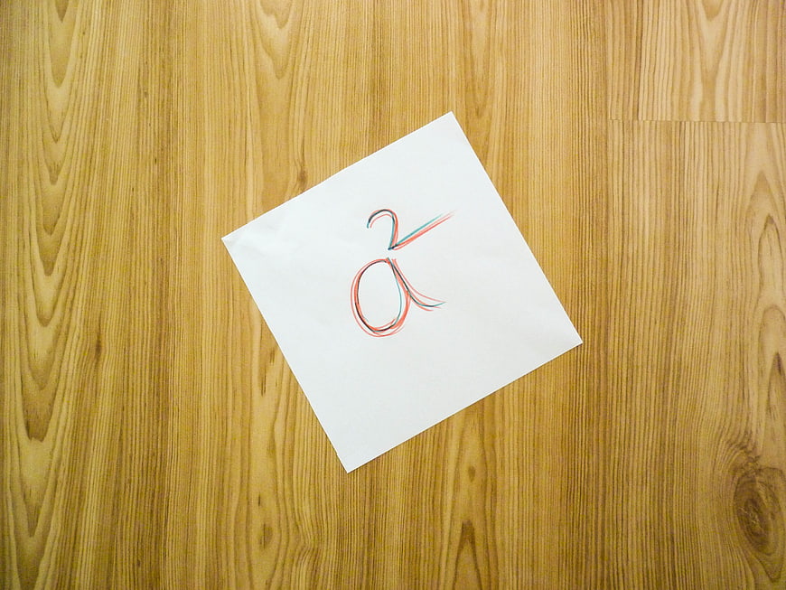 Handwritten mathematical symbol on white paper on wooden table