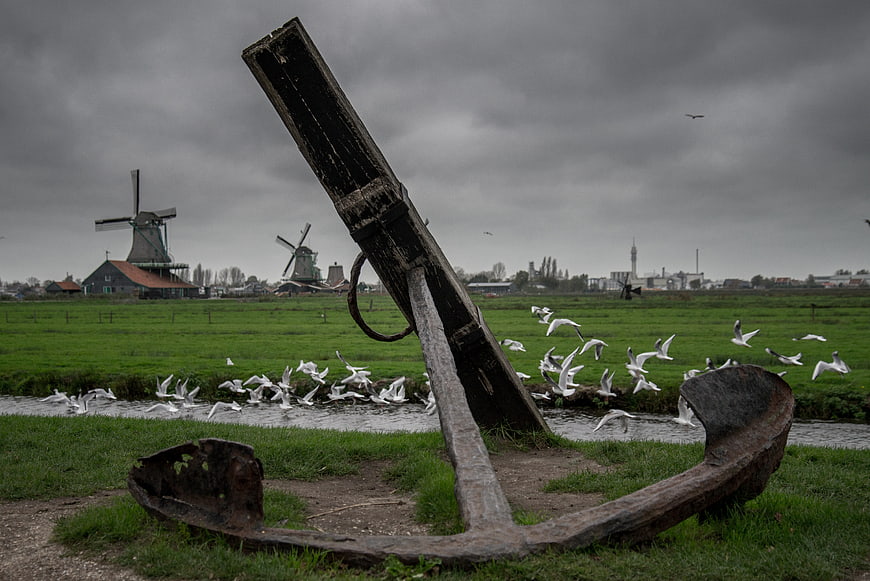 Rusty Anchor in Foreground with Dutch Windmills and Birds