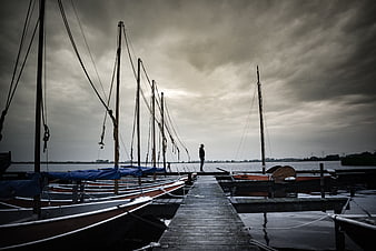 Solitary Man Standing on Wooden Pier at Dusk