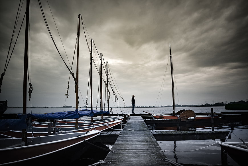 Solitary Man Standing on Wooden Pier at Dusk