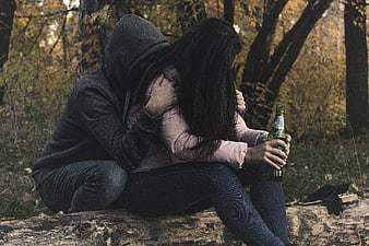 Couple embracing in autumn forest with beer bottle
