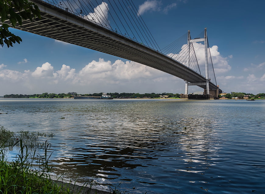 Cable-stayed bridge over river with cargo barge
