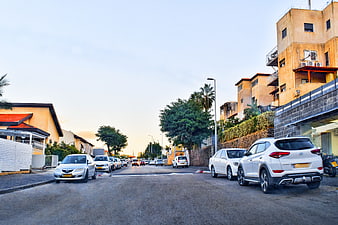 Residential street with parked cars and apartment buildings at sunset