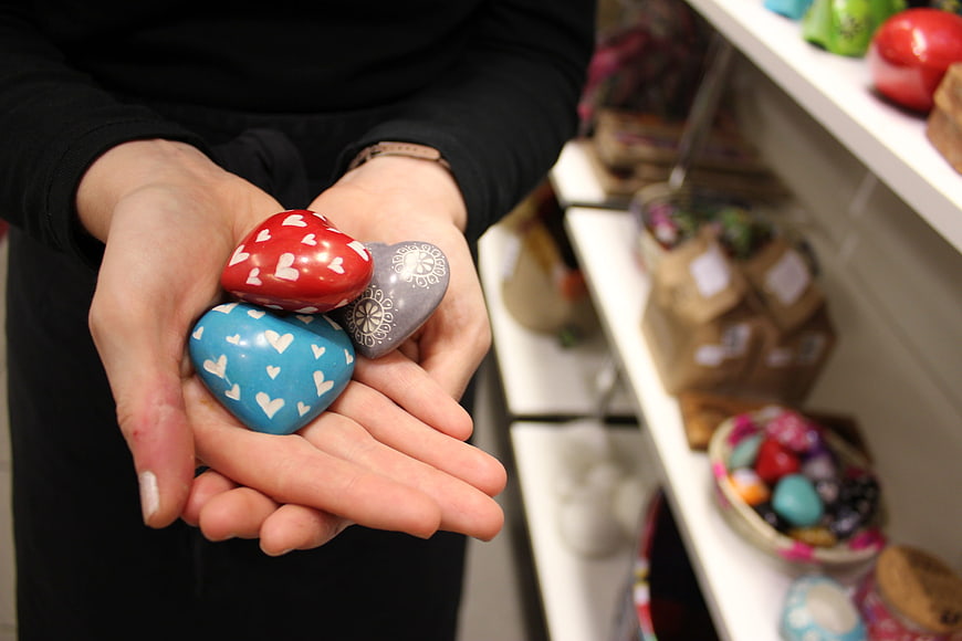 Hands Holding Decorative Heart-Shaped Stones in a Craft Shop
