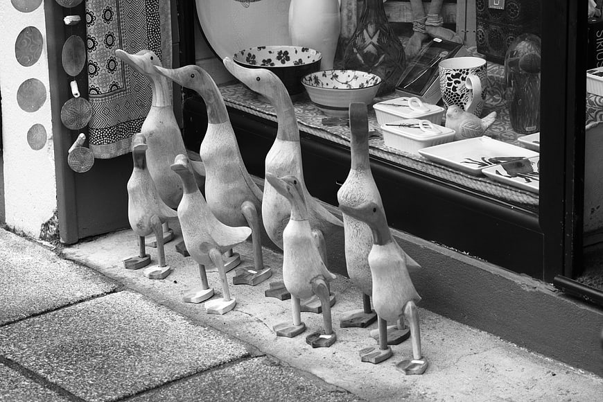 Black and white photo of wooden duck figurines on a shop sidewalk