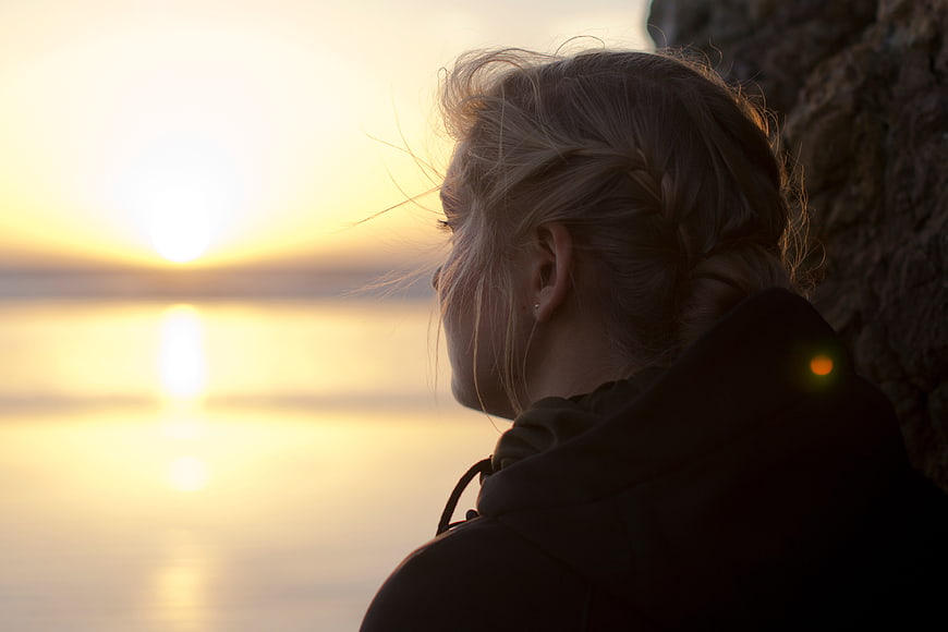 Blonde Woman Silhouette Watching Sunset Over Calm Water