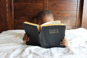 Young Boy Reading Holy Bible in Bed
