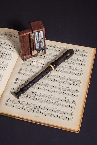 Vintage wooden recorder and metronome on old sheet music