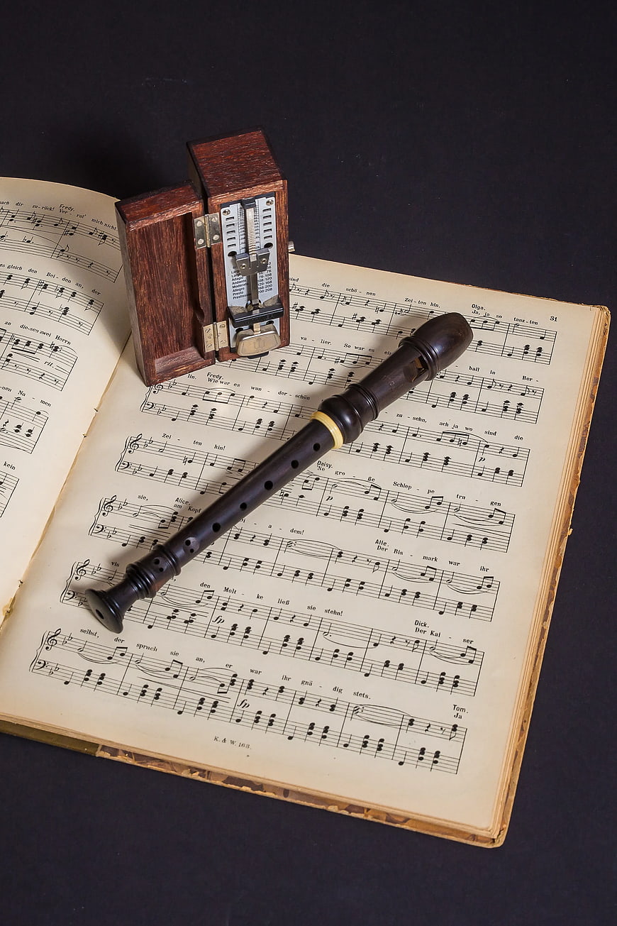 Vintage wooden recorder and metronome on old sheet music