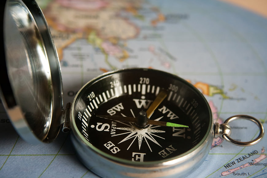 Vintage magnetic compass resting on a world map