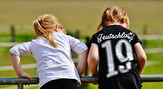 Two young girls leaning on a metal railing outdoors