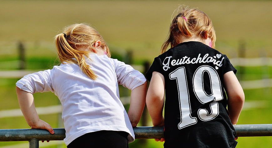 Two young girls leaning on a metal railing outdoors
