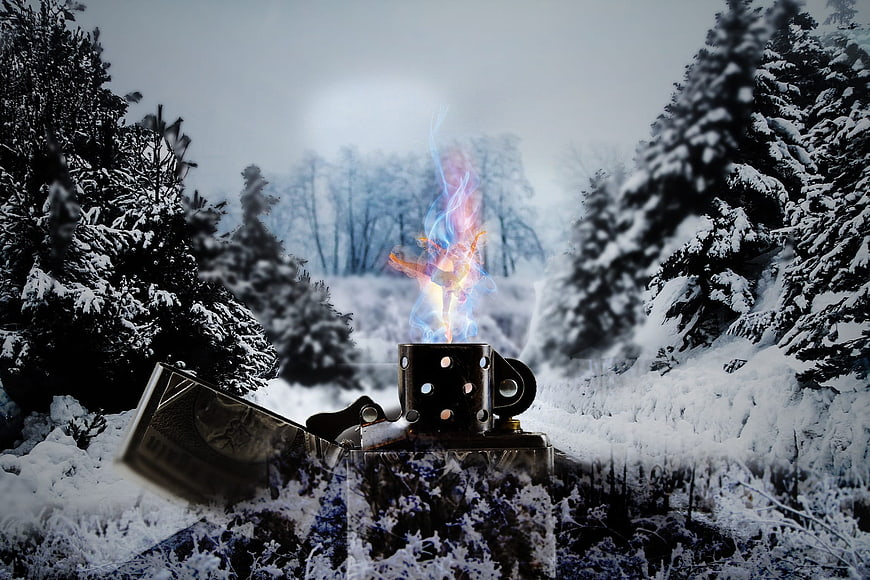 Lighter with colorful flame in snowy winter forest landscape