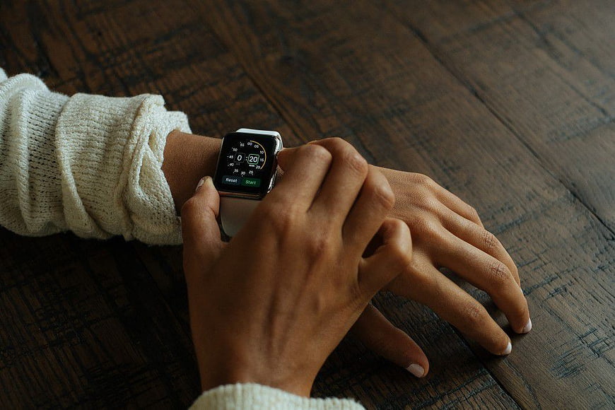 Person Checking Timer on Smartwatch on Wooden Table