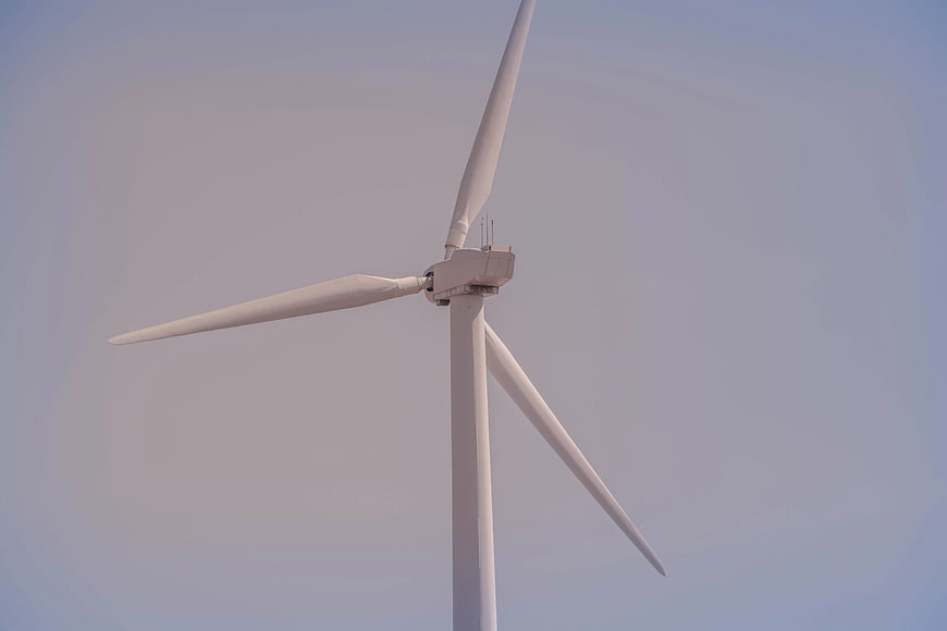 White Wind Turbine Against Clear Blue Sky
