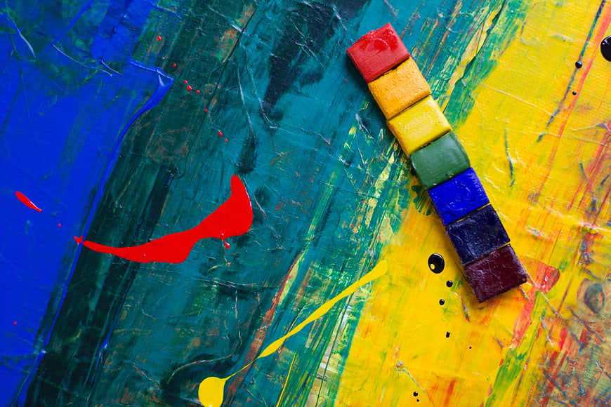 Rainbow paint sticks on colorful abstract painted background