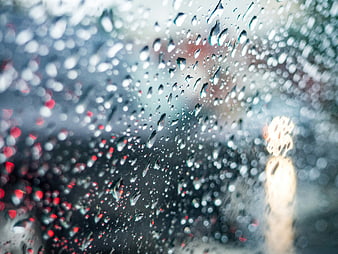 Raindrops on glass window with blurred city lights background