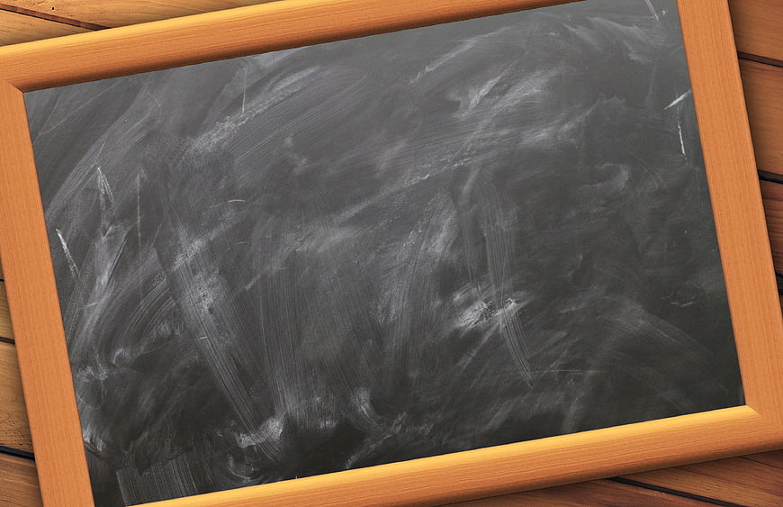 Empty wooden chalkboard with chalk dust on wooden background
