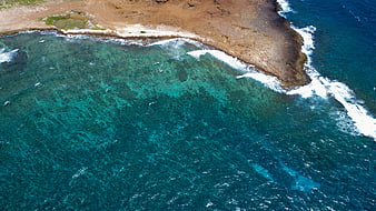 Aerial View of Turquoise Ocean Waves Crashing on Rocky Coastline