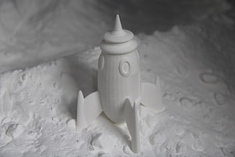 White 3D Printed Rocket Ship Model on Textured Surface