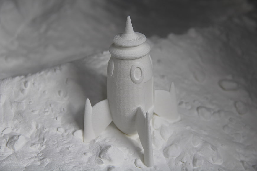 White 3D Printed Rocket Ship Model on Textured Surface