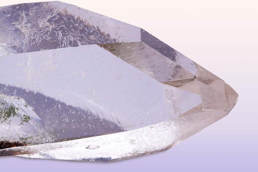 Close-up of raw clear quartz crystal point on white background