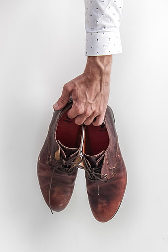 Man Holding Brown Leather Shoes on White Background
