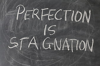 Perfection is stagnation handwritten on a chalkboard