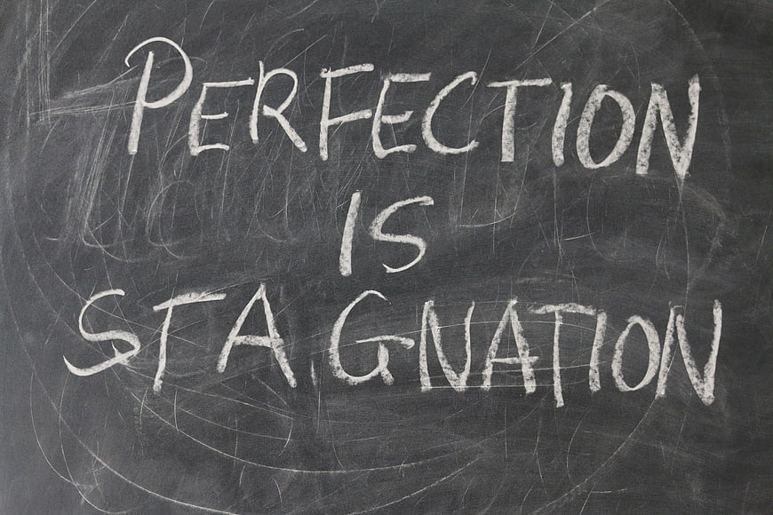 Perfection is stagnation handwritten on a chalkboard