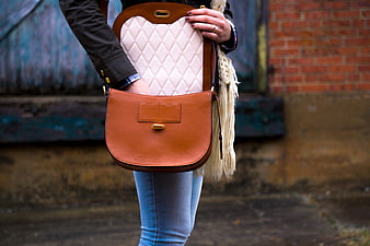 Woman holding tan and cream quilted leather handbag