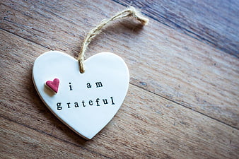 White ceramic heart ornament with 'I am grateful' text on wood