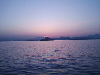 Serene Sunset Over Sea with Distant Castle Silhouette