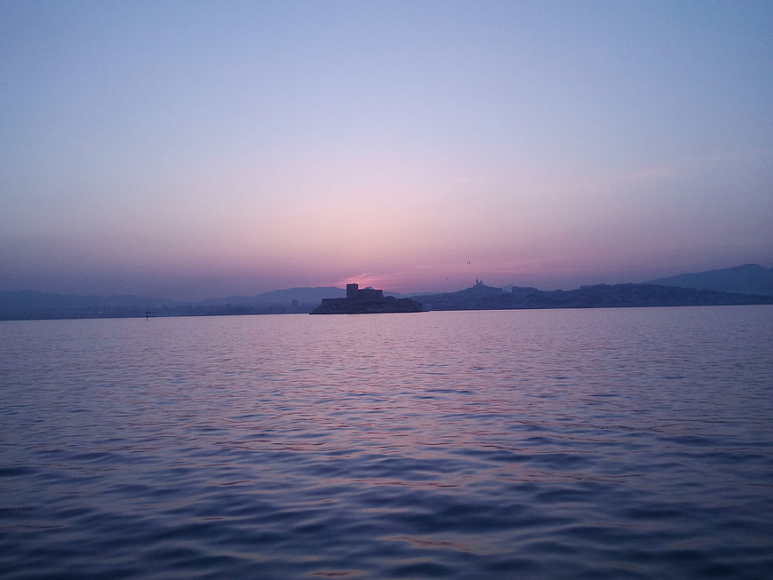 Serene Sunset Over Sea with Distant Castle Silhouette