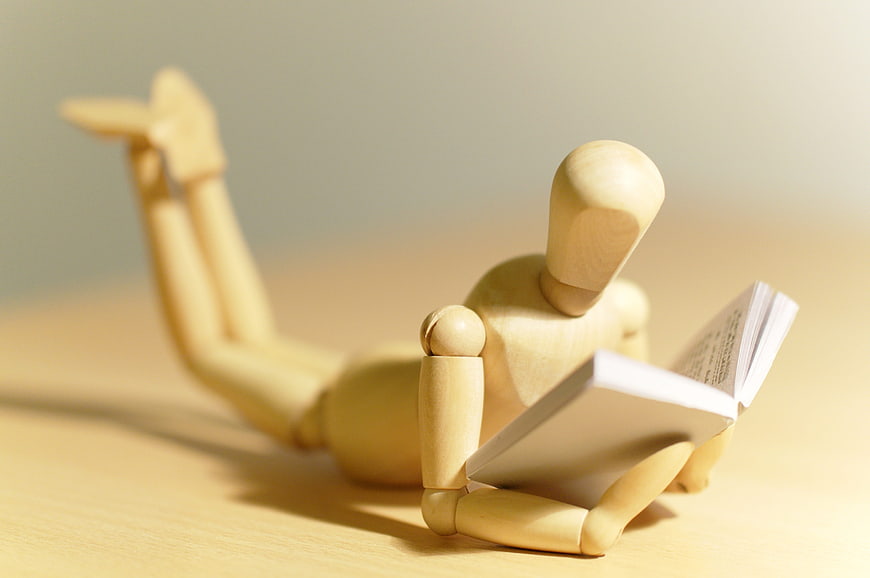 Wooden mannequin reading a book on a desk