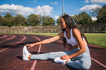Athletic woman stretching on outdoor running track