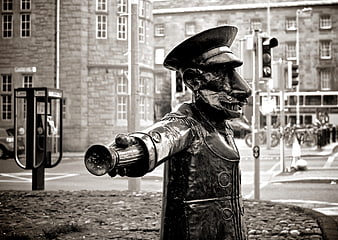 Black and white statue of a conductor with a megaphone in a city