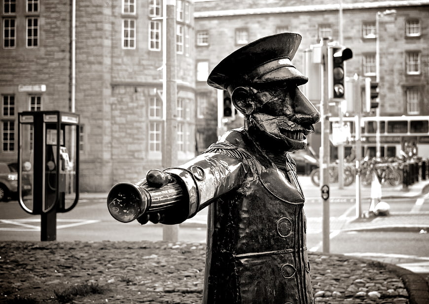 Black and white statue of a conductor with a megaphone in a city