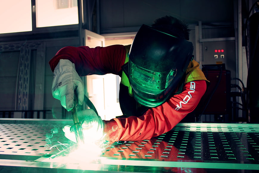 Industrial Welder Working with Bright Sparks in Factory