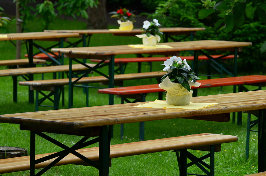 Outdoor Wooden Picnic Tables With Floral Centerpieces In Garden