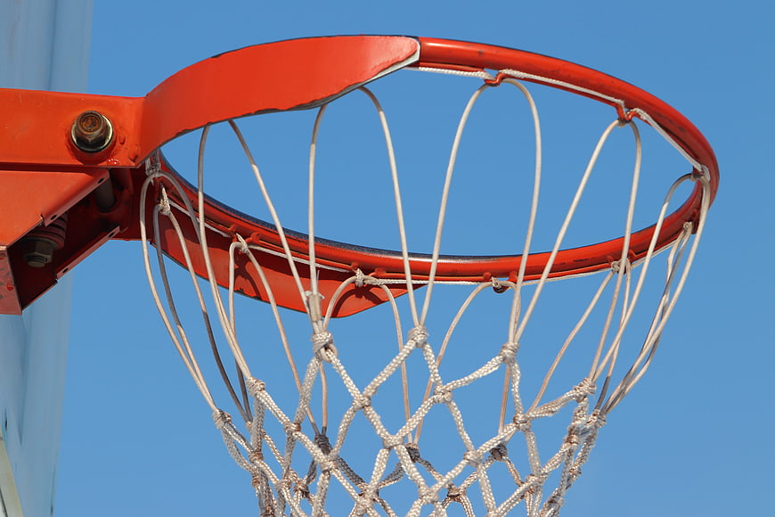 Close-up of red basketball hoop and white net against clear blue sky